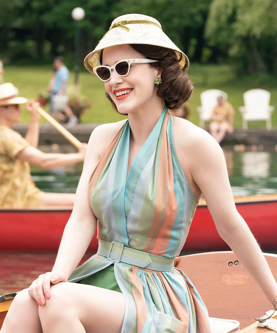 Rachel Brosnahan in a colorful dress on a boat, resting on her hand.